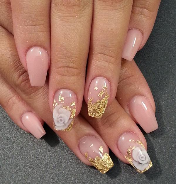 Nude and gold nail art design. Based with nude nail polish, the nails are then sprinkled with gold nail polish up to the tips and topped with flower embellishments.