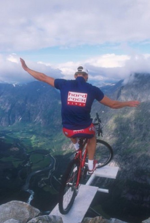 art of balance  photo - Unicycle bicycle show on the edge of a cliff