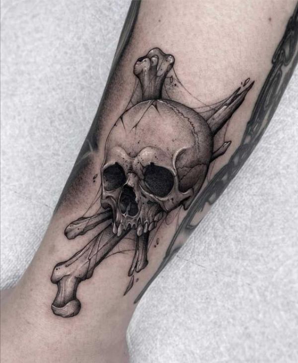 Black and grey skull and bones tattoo on arm