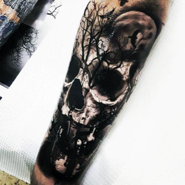 Dark skull and tree forearm tattoo