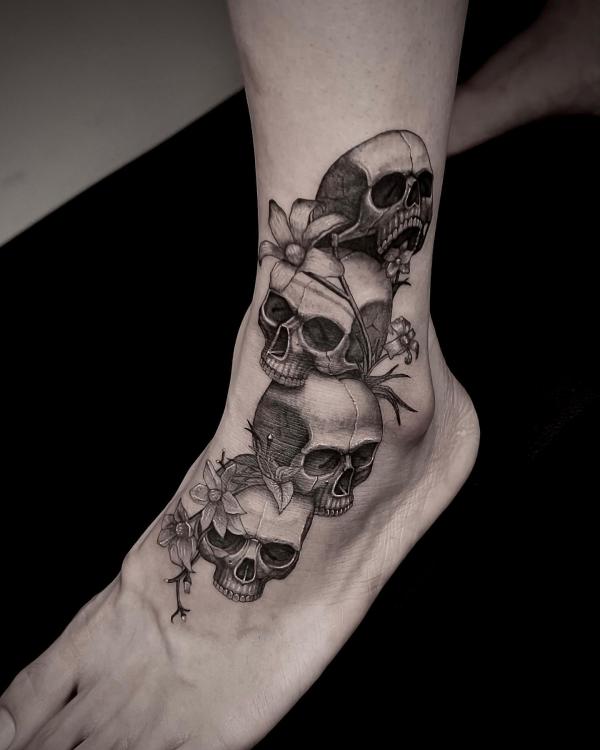 Four skull foot tattoo