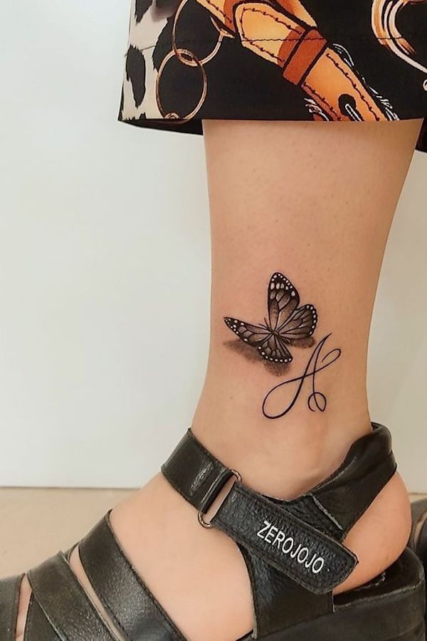 A vivid butterfly tattoo with initials on the ankle 