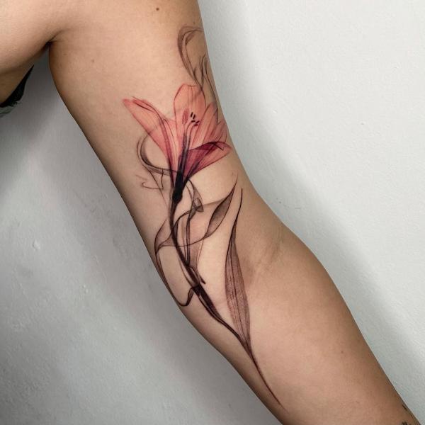 Dainty lily flower bicep tattoo