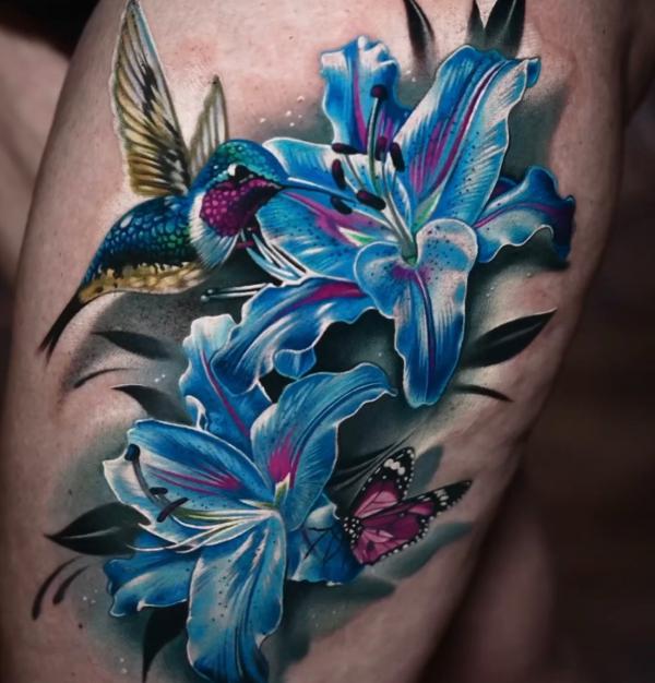 Realistic blue lily flowers tattoo with hummingbird and butterfly