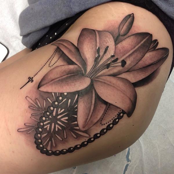 Realistic lily tattoo on side of hip in dark skin tones