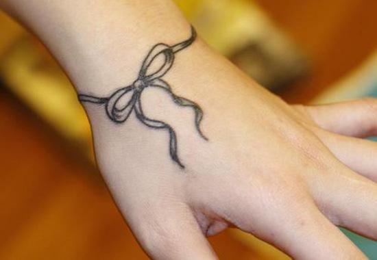 Black and gray ribbon tattoo on wrist