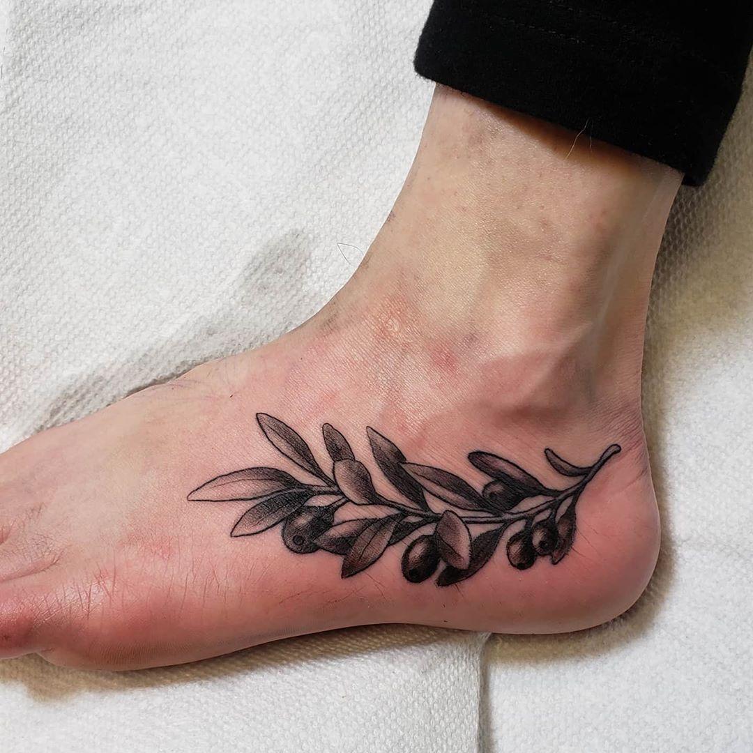 Black and white tattoo with ankle bracelet with feather in Native American style