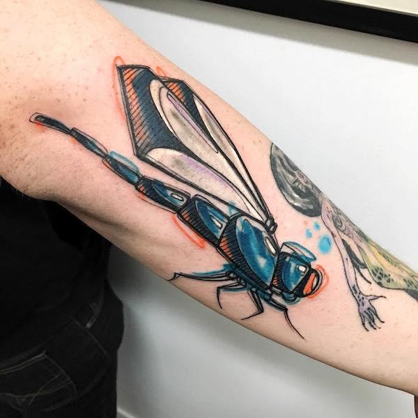 Forearm tattoo with a dragonfly in sketch color style