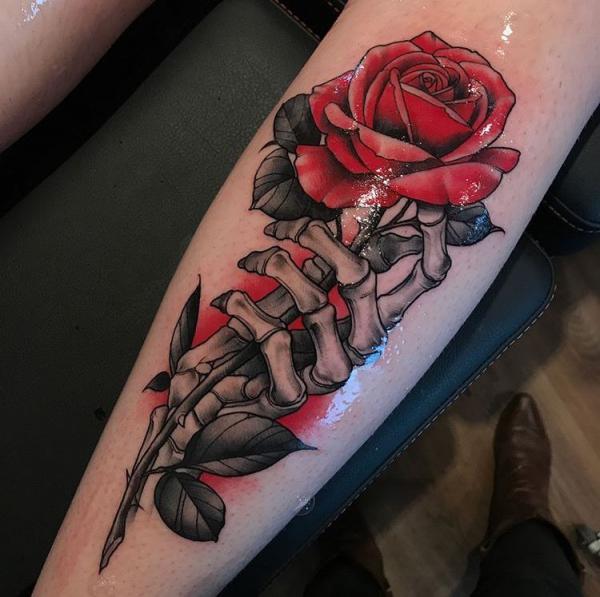 A skeleton hand holding a red rose