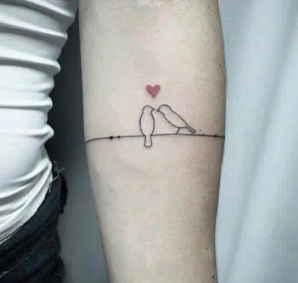 Two birds on a string with a heart outline tattoo