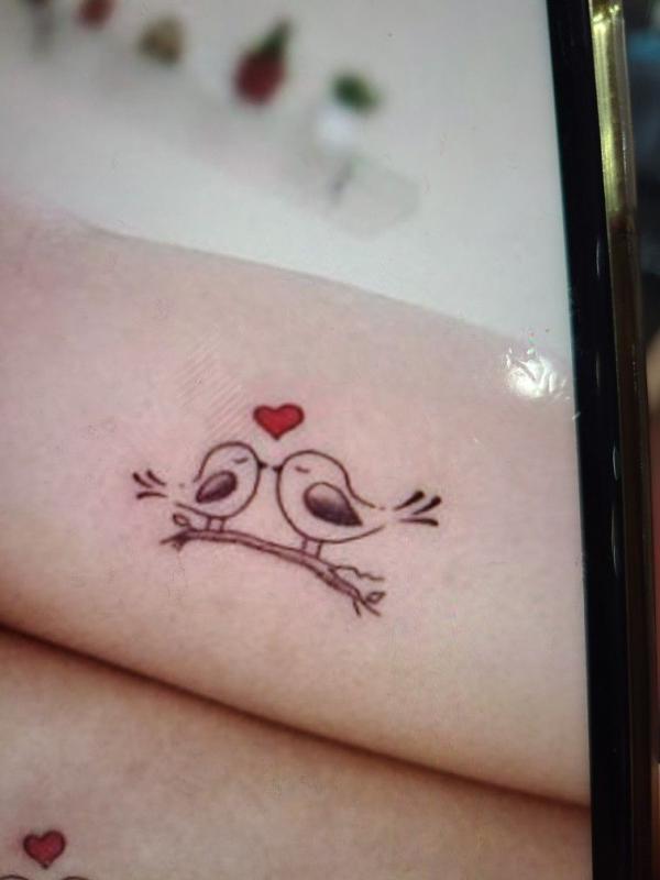 Two birds perched on branch with heart symbol