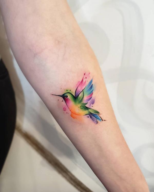 Small watercolor hummingbird tattoo on forearm