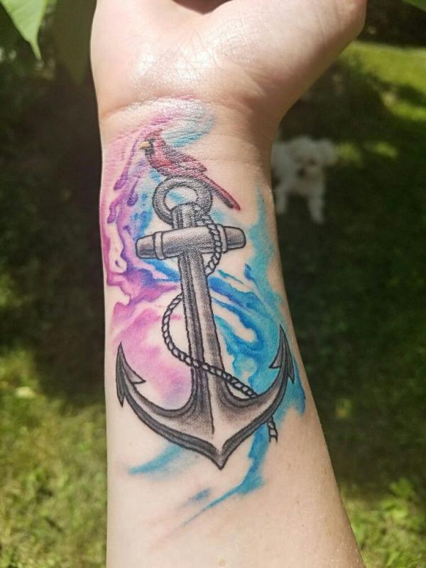 Watercolor anchor and bird tattoo on forearm