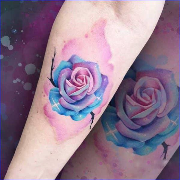 Watercolor pink and blue rose with stars tattoo on forearm