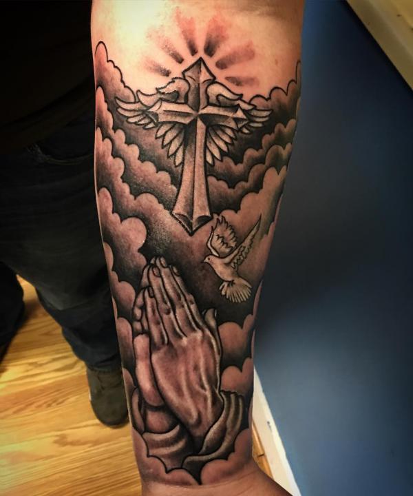 Praying hands Cross and a flying dove with clouds tattoo on forearm