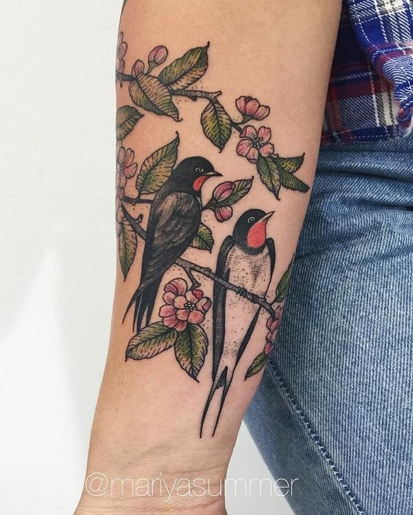 Two Swallows perched on branch with flower and leaves
