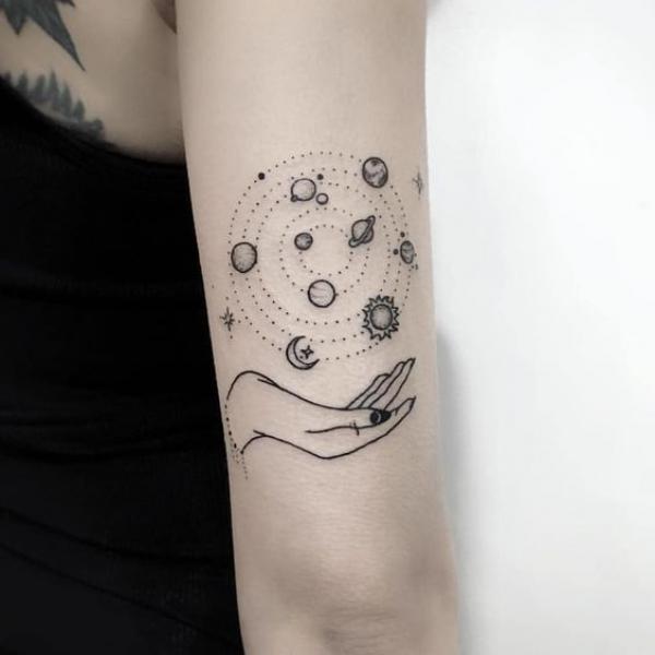 Hand holding circular solar system tattoo