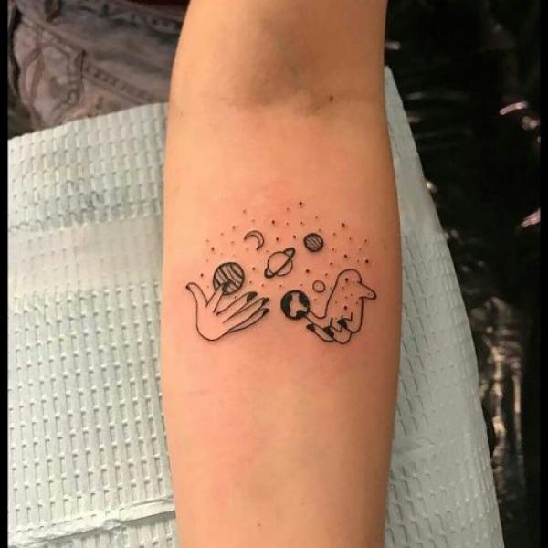 Hands holding solar system tattoo below elbow