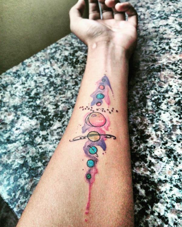 Watercolor solar system tattoo on inner forearm