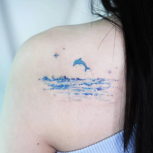 Dolphin and ocean shouder blade tattoo