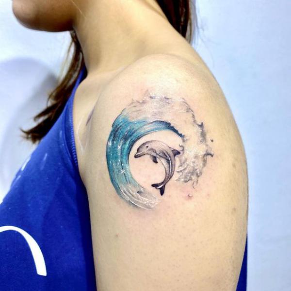Dolphin dancing in wave shoulder tattoo