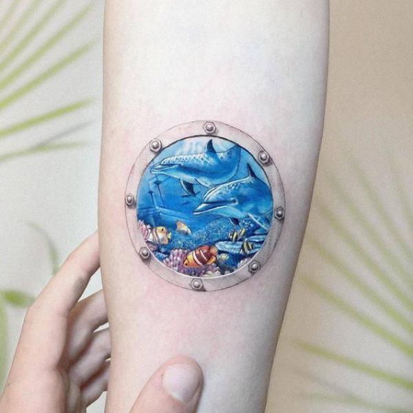 Dolphin in sea floor frame tattoo in feminine style