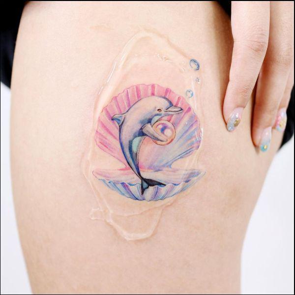 Dolphin jumping out of shell tattoo