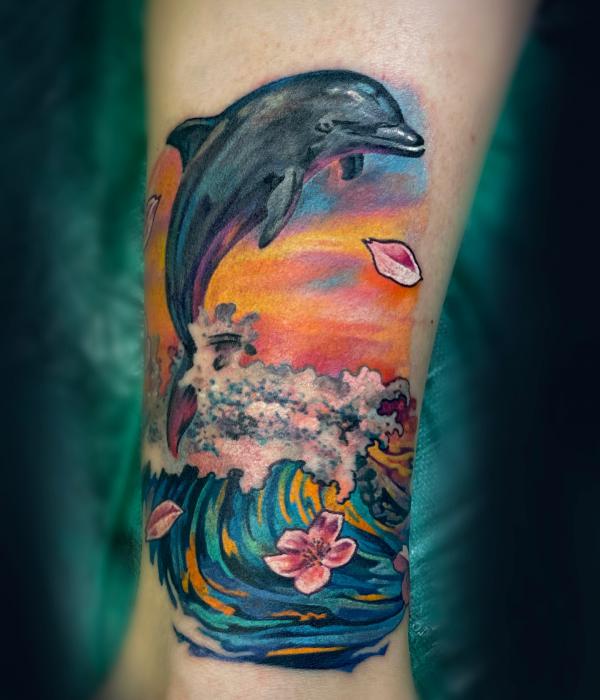 Dolphin jumping out of wave tattoo with petals of cherry blossom tattoo