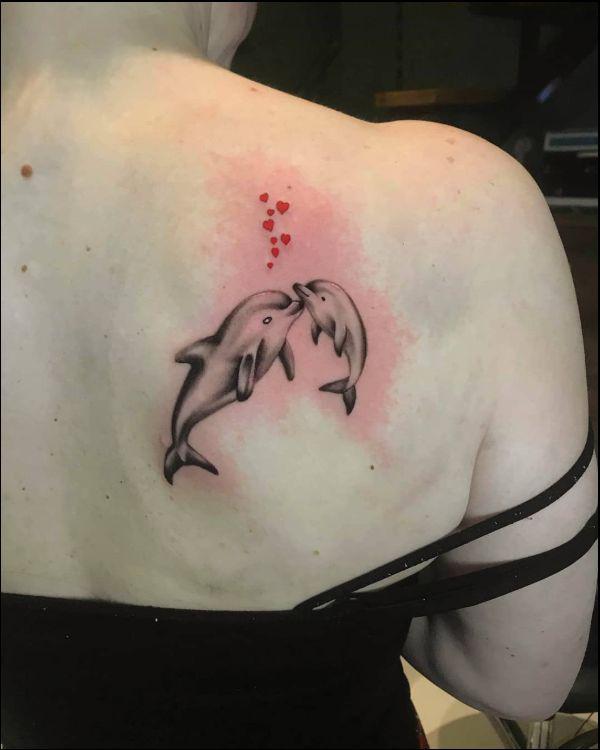 Dolphin mother and baby with heart symbols shoulder blade tattoo