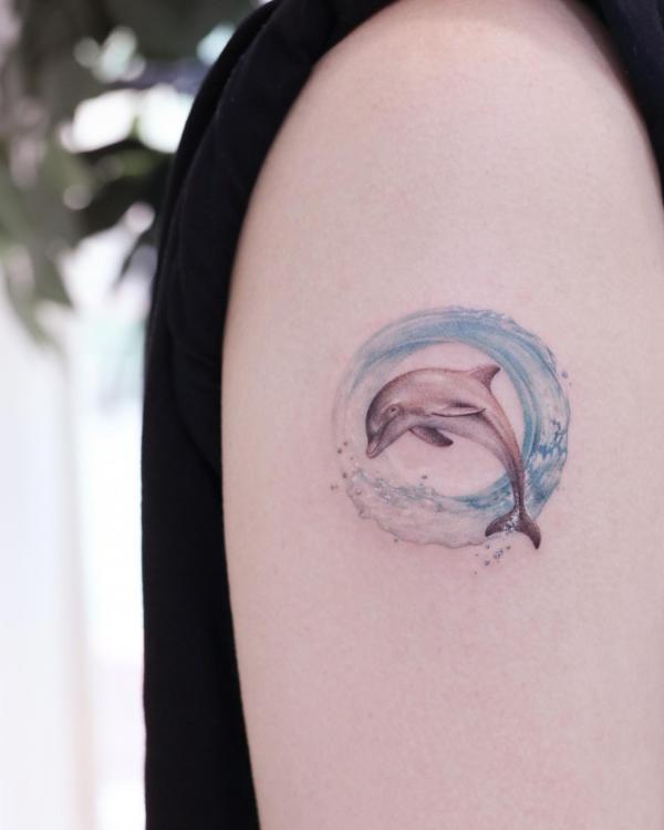 Feminine dolphin in wave circle tattoo