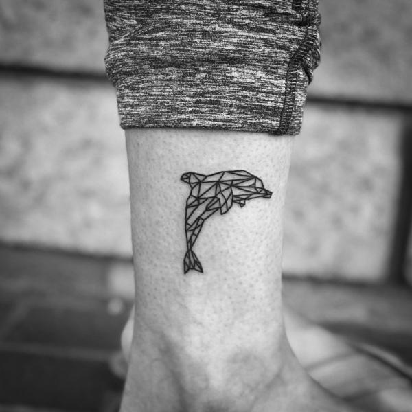 Geometric dolphin tattoo above ankle
