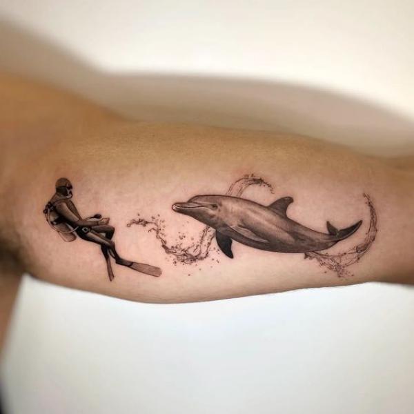 Scuba diver and dolphin bicep tattoo
