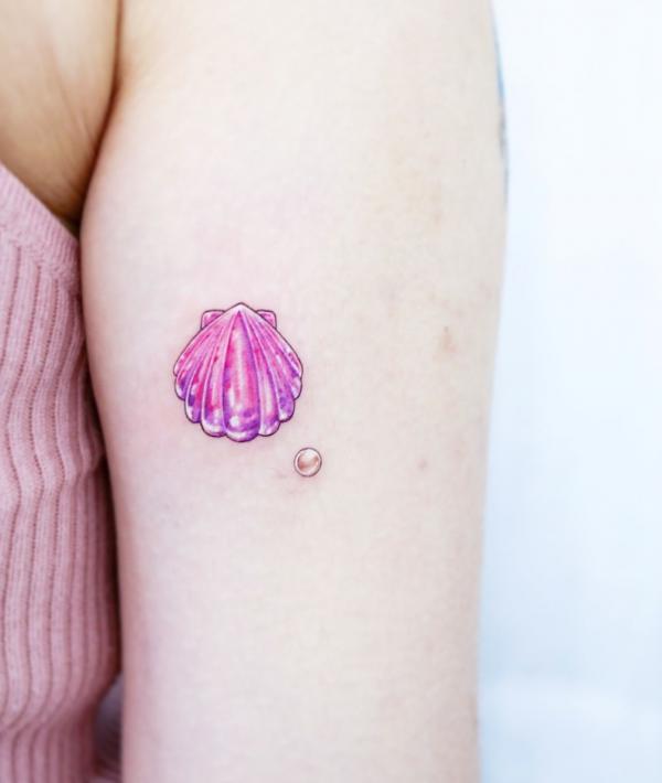Cute pink shell and pearl upper arm tattoo