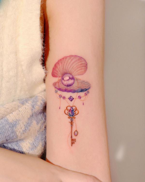 Feminine shell with pearl pendant and key tattoo