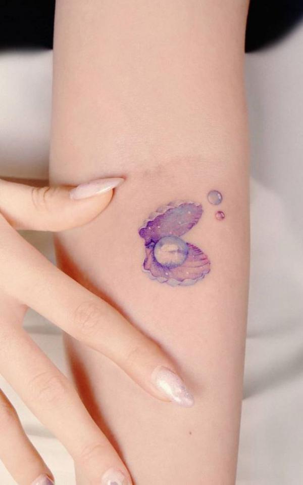 Purple shell with pearls tattoo below inner elbow
