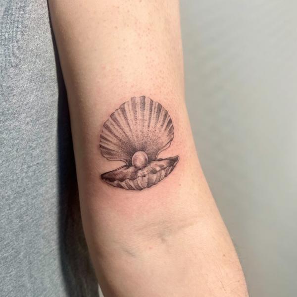 Shell with a pearl tattoo above elbow