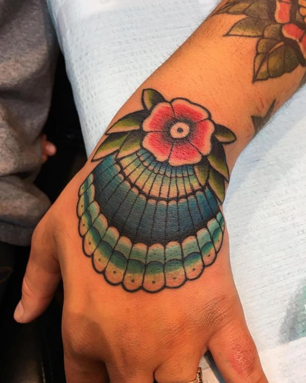 Traditional blue shell with red flower hand tattoo