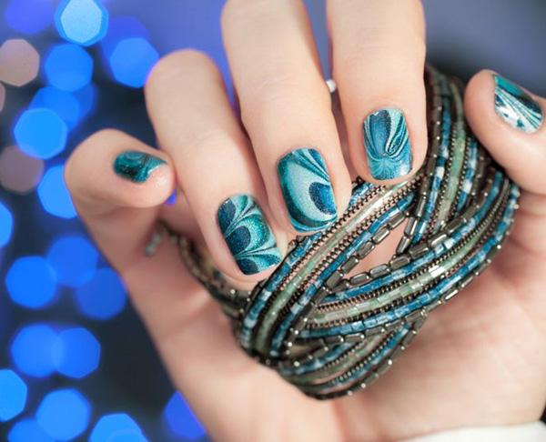 Amazing looking flower patterned water marble nail art design in dark to light forest green shades and silver dust on top.