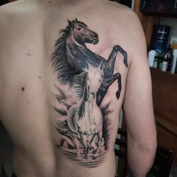 Black and white horses tattoo on one side of back