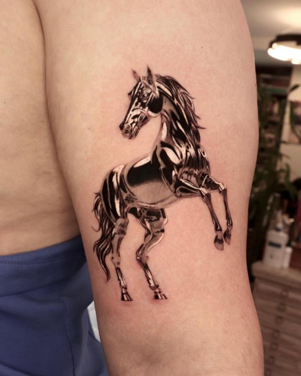 Golden horse tattoo above elbow