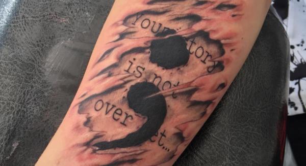Your story is not over yet semicolon tattoo on ripped skin