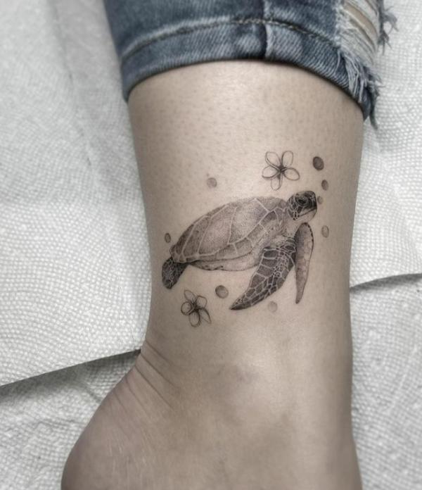 Black and grel turtle with plumeria ankle tattoo