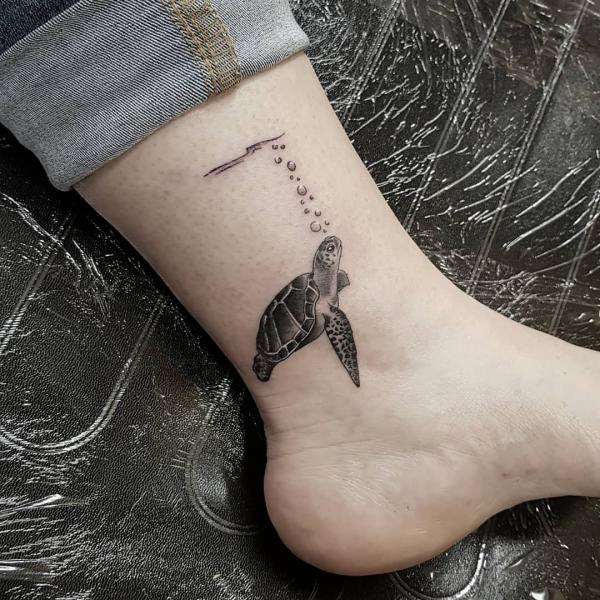 Sea turtle in water ankle tattoo