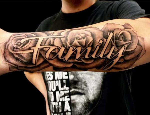Negative space Family font on roses forearm tattoo