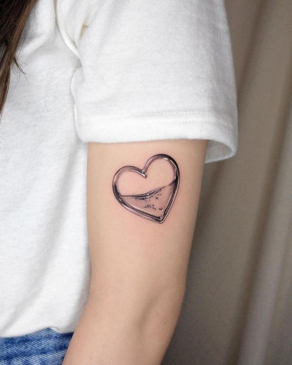 A small tattoo of a heart shaped ring half filled with water