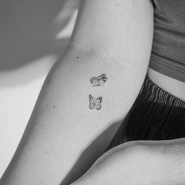 Minimalist tattoo of two butterflies on the arm