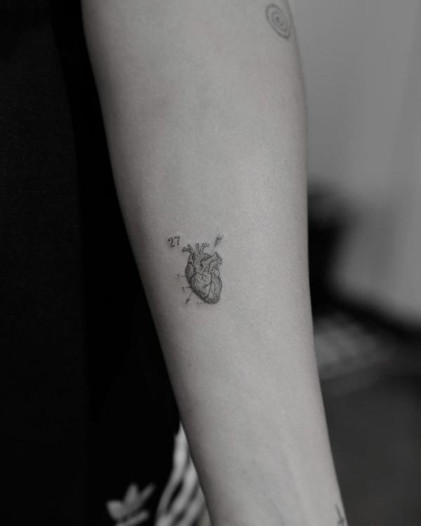 Minimalist tattoo of a real heart pierced by arrows