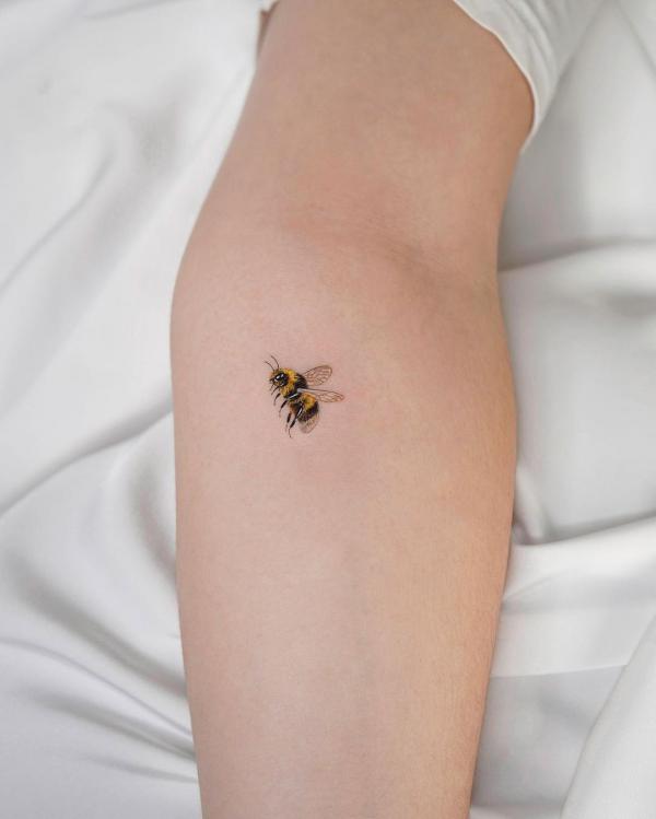 A tiny bee tattoo on the elbow