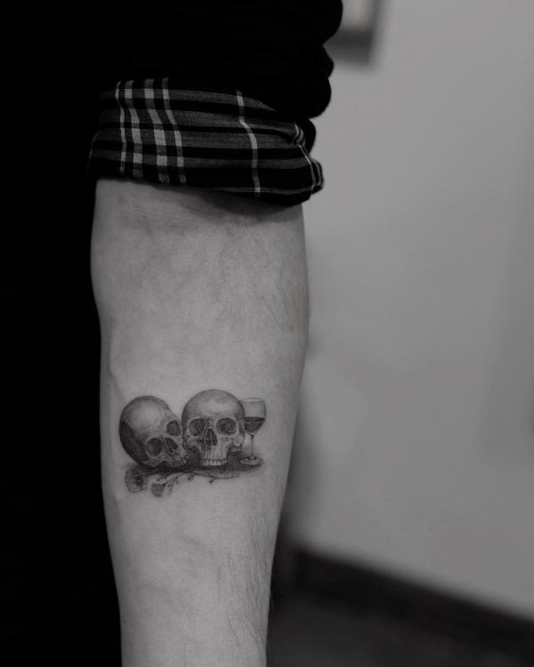 Minimalist tattoo of Two skulls with a wine goblet