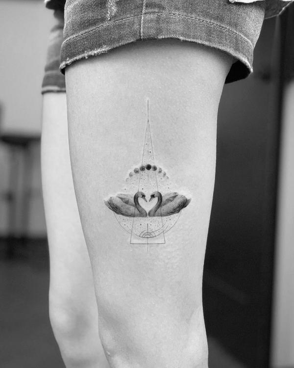 A minimalist tattoo of two swans, facing one another in the radiant sunlight